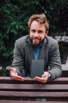 Portrait handsome bearded man wearing glasses blue shirt.Man near university library, reading book and relaxing. Blurred background.Horizontal, film effect.