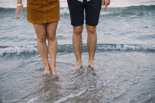 Beautiful couple holding hands and walks at the sea shore in the evening