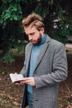 Portrait handsome bearded man wearing glasses blue shirt.Man near university library, reading book and relaxing. Blurred background.Horizontal, film effect.