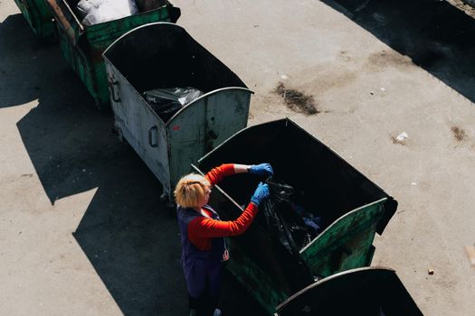 An old woman throws out trash. Trash can. The outside. Odessa City, Ukraine, May 2019. true