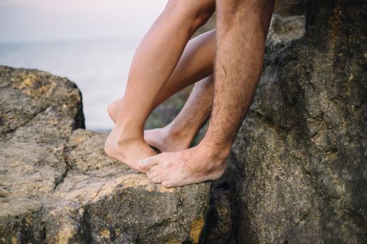 close up legs of kissing couple near the sea on the rocks. love