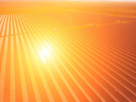 Aerial top view of a solar panels power plant. Photovoltaic solar panels at sunrise and sunset in countryside from above. Modern technology, climate care, earth saving, renewable energy concept