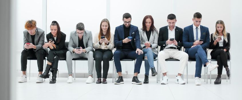 group of diverse young business people looking at their smartphone screens. photo with copy space