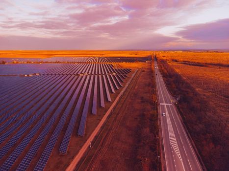 Aerial top view of a solar panels power plant. Photovoltaic solar panels at sunrise and sunset in countryside from above. Modern technology, climate care, earth saving, renewable energy concept