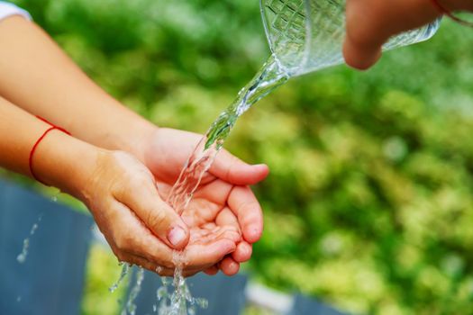 The child washes his hands in the street. Selective focus. nature