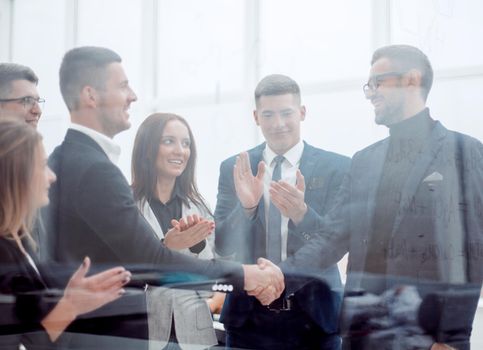 through the glass. business people meet each other with a handshake. business concept