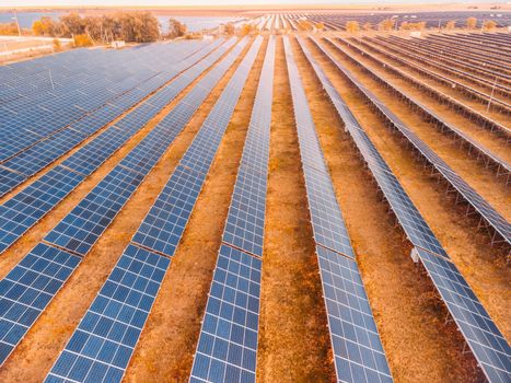 Aerial top view of a solar panels power plant. Photovoltaic solar panels at sunrise and sunset in countryside from above. Modern technology, climate care, earth saving, renewable energy concept