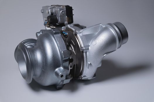 New turbocharger with aluminum cold section. on a gray contrasting background. car engine turbocharger. spare parts.