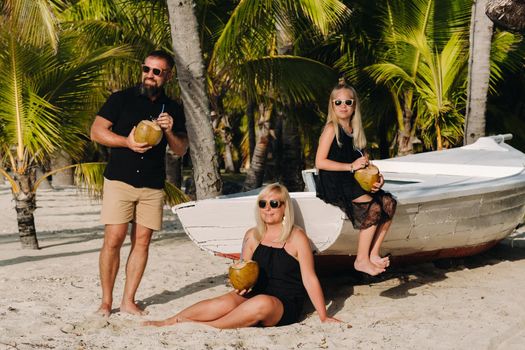 a stylish family in black clothes with coconuts in their hands on the beach of the island of Mauritius.Beautiful family on the island of Mauritius in the Indian ocean.