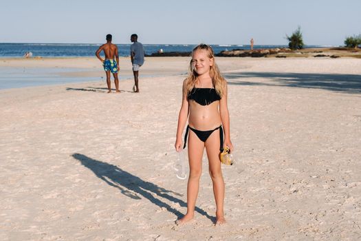 A charming little girl is lying on the beach and drawing on the sand.A little girl lies on the beach of the island of Mauritius.