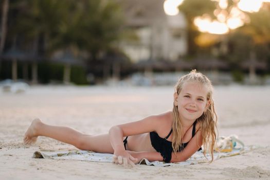 A charming little girl is lying on the beach and drawing on the sand.A little girl lies on the beach of the island of Mauritius.