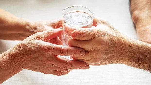 Grandma gives grandfather a glass of water. Selective focus. food.