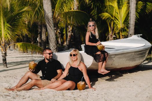 a stylish family in black clothes with coconuts in their hands on the beach of the island of Mauritius.Beautiful family on the island of Mauritius in the Indian ocean.