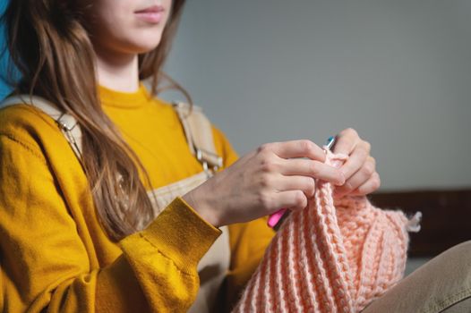 female hands close-up, crocheting clothes on the sofa at home, handmade.