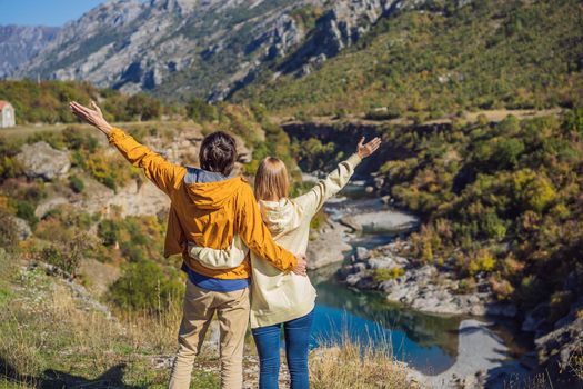 Montenegro. Happy couple man and woman tourists on the background of Clean clear turquoise water of river Moraca in green moraca canyon nature landscape. Travel around Montenegro concept.