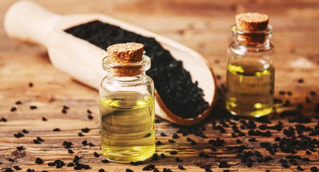 Black cumin essential oil in a small bottle. Selective focus. nature.