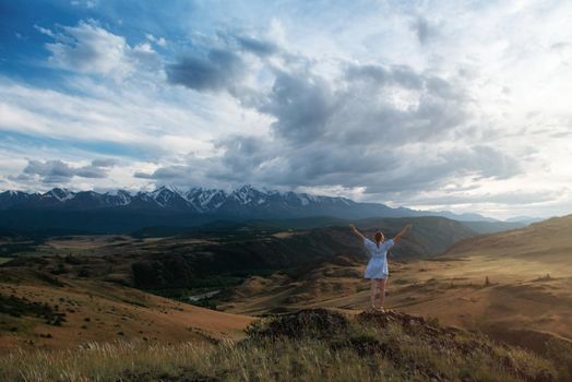 Woman in blue dress in summer Altai mountains in Kurai steppe