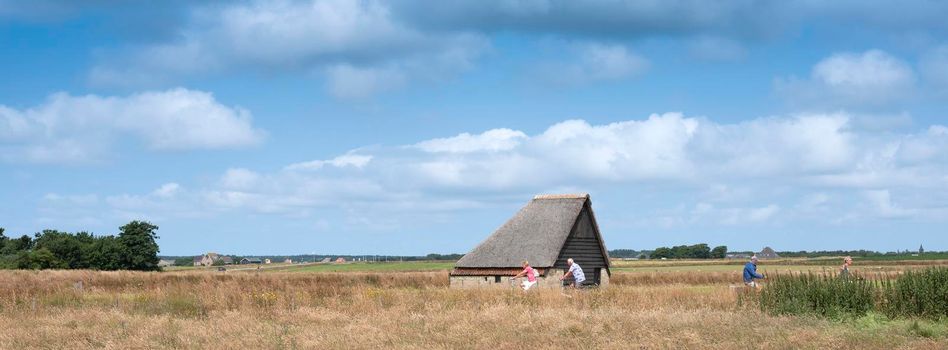 Den Burg, Netherlands, 19 july 2021: people ride bicycle near typical barn on the island of texel in summer in holland
