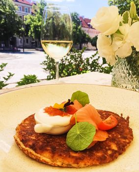 Potato fritter pancake with red caviar, salmon and sour cream in luxury restaurant outdoors in summer.