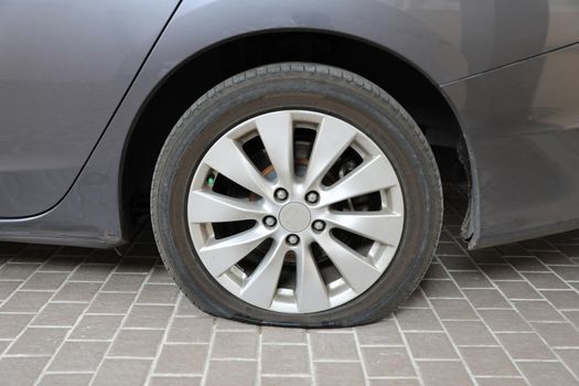 Car flat tire on gray tiled floor