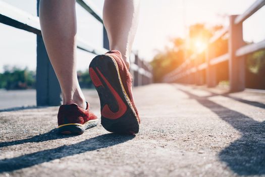 On a green background, a woman walks and runs while wearing running shoes. Exercise for health is a notion.