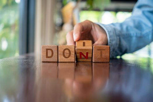 A woman turns a wooden cube with the words do it or don't as a metaphor for making a decision.