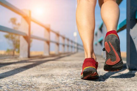 On a green background, a woman walks and runs while wearing running shoes. Exercise for health is a notion.