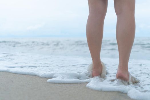 On a sand tropical beach with a blue sky background, a woman's feet walk slowly and relax.