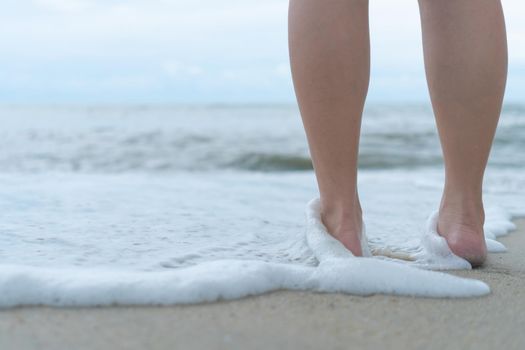 On a sand tropical beach with a blue sky background, a woman's feet walk slowly and relax.