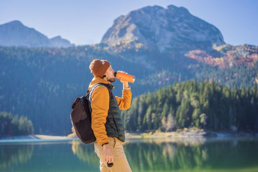 Man tourist in background of Panoramic morning view of Black Lake Crno Jezero. Calm summer scene of Durmitor Nacionalni Park, Zabljak location, Montenegro, Europe. Beauty of nature concept background. Travel around Montenegro concept.