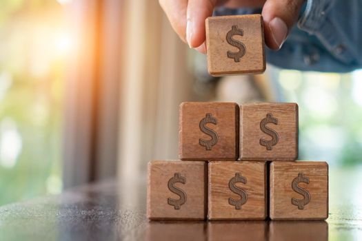 A set of wooden cubes on a table with a dollar symbol on the background as a metaphor for money or wealth saving and financial freedom.