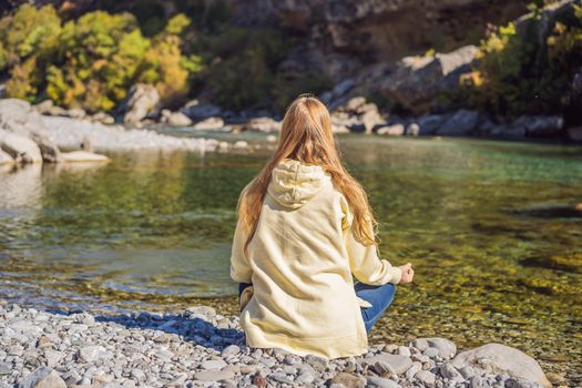 Montenegro. Woman tourist meditates on the background of Clean clear turquoise water of river Moraca in green moraca canyon nature landscape. Travel around Montenegro concept.