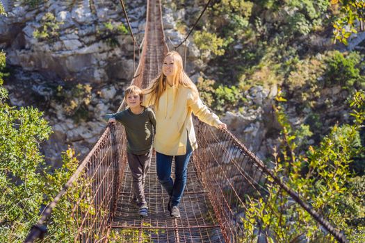 Mom and son tourists on Old rusty bridge. Attraction Long extreme suspension iron bridge across the river Moraca. Sights of Montenegro. Landmark Montenegro.