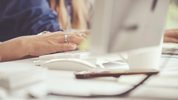 Close up shot of businesswoman hand typing and working on desktop computer on the office desk. Business communication and workplace concept.