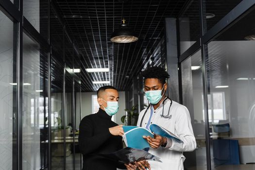 Asian patient with x-rays asks an African doctor about treatment of pneumonia and pleurisy. Black surgeon consult and help Asian man