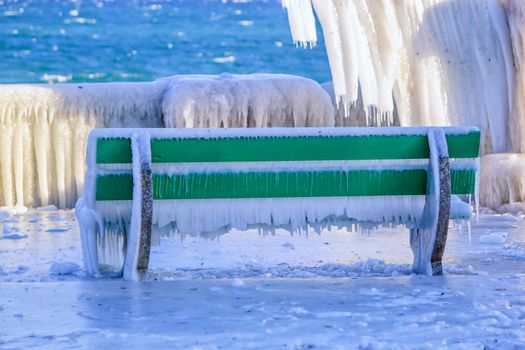 One frozen bench because of cold winter temperature and waves at Versoix, Switzerland