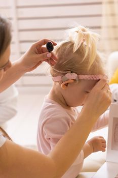 Cochlear implant for baby. Deaf child with hearing aid plays in living room