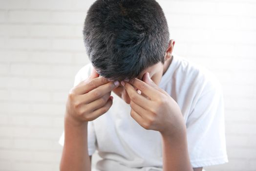 teenage boy covering his face with had .