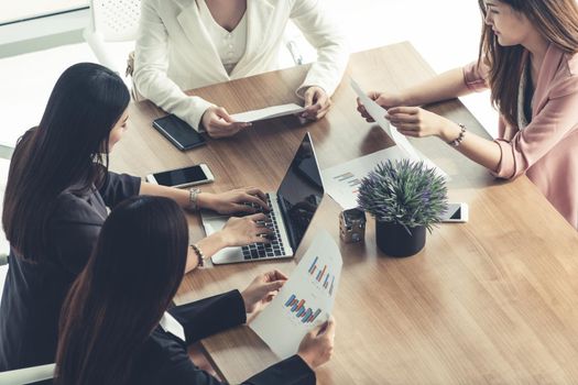 Businesswoman in group meeting discussion with other businesswomen colleagues in modern workplace office with laptop computer and documents on table. People corporate business working team concept.