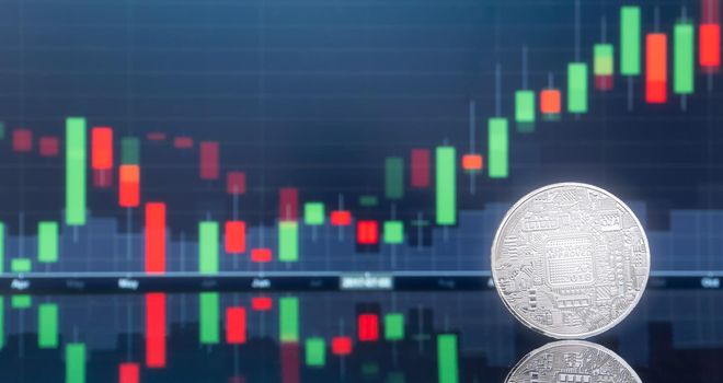 Initial coin offering (ICO) and digital money investing concept - Physical metal digital coins with blue global trading exchange market price chart in the background.