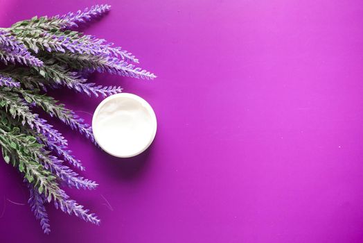 beauty cream and lavender flower on purple background .
