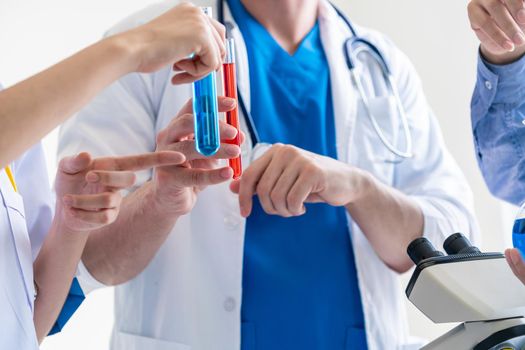 Group of scientists wearing lab coat working in laboratory while examining biochemistry sample in test tube and scientific instruments. Science technology research and development study concept.