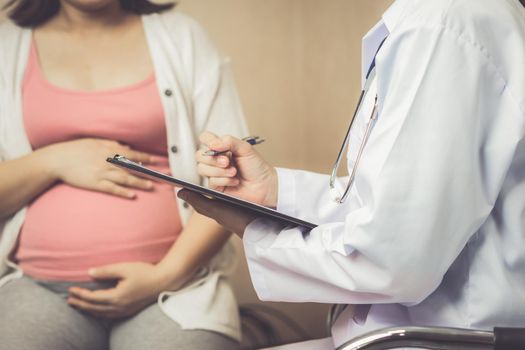 Happy pregnant woman visit gynecologist doctor at hospital or medical clinic for pregnancy consultant. Doctor examine pregnant belly for baby and mother healthcare check up. Gynecology concept.