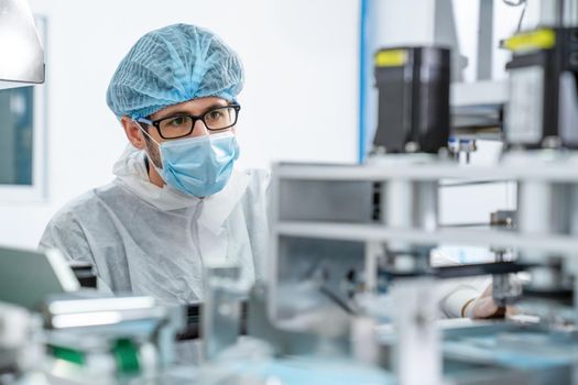 Production line worker with face mask working in electronic factory . Concept of protective action and quarantine to stop spreading of Coronavirus Disease 2019 or COVID-19 .