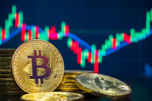 Bitcoin and cryptocurrency trading system concept - Image of Physical bitcoin pile against market price chart as blur background.