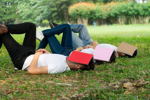 Funny students sleeping with books covering their face. Lazy and relaxation concept.