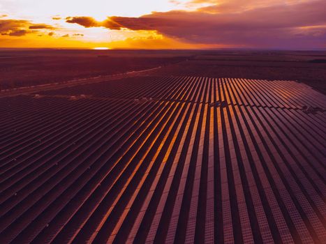 Aerial top view of a solar panels power plant. Photovoltaic solar panels at sunrise and sunset in countryside from above. Modern technology, climate care, earth saving, renewable energy concept