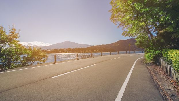 Beautiful road scenery with lake and mountain landscape background. Concept of travel, transportation, road trip and freedom.