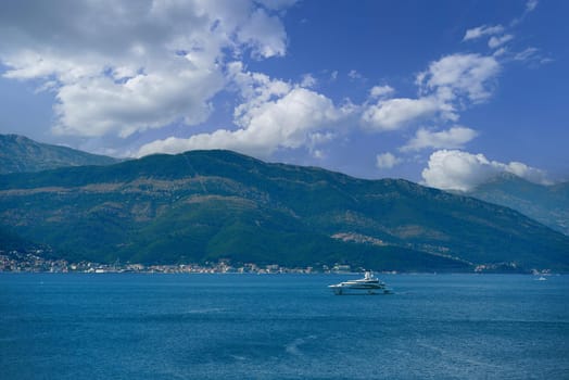 Seascape with luxury yacht against the backdrop of mountains in Montenegro.
