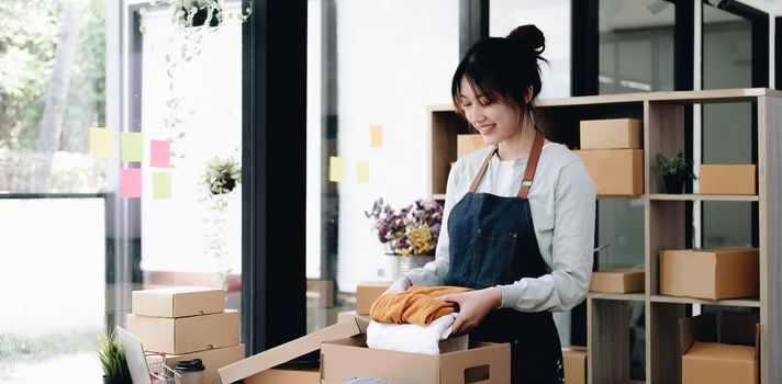 young start up small business owner packing cardboard box at workplace. freelance woman seller prepare parcel box of product for deliver to customer. Online selling, e-commerce, shipping concept.